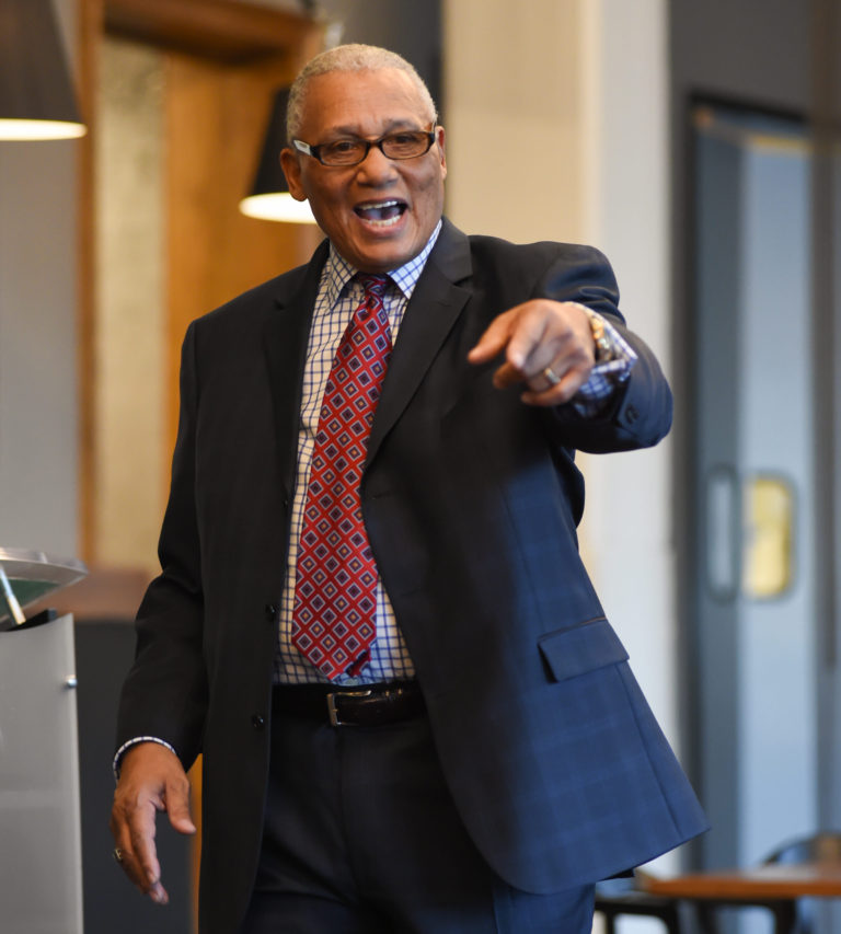 A man in a suit and tie pointing to the side.